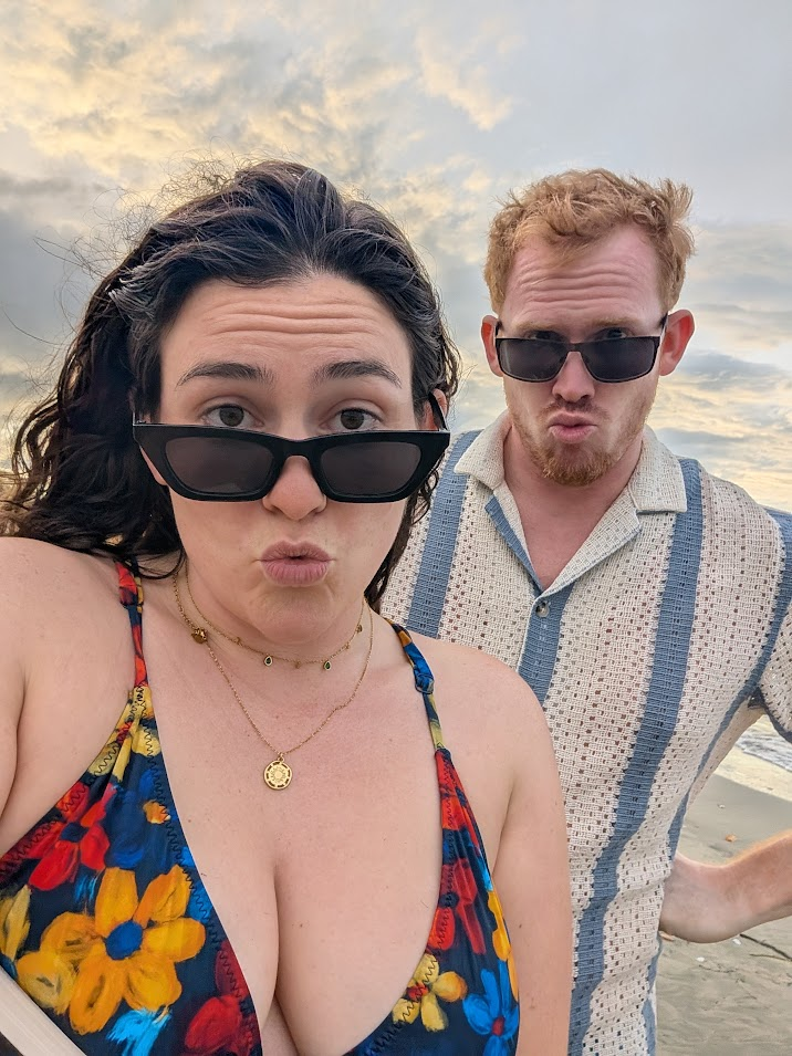 Ellie and John pulling silly faces on the beach at dusk